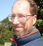 A person wearing glasses and a blue jacketDescription automatically generated with low confidence